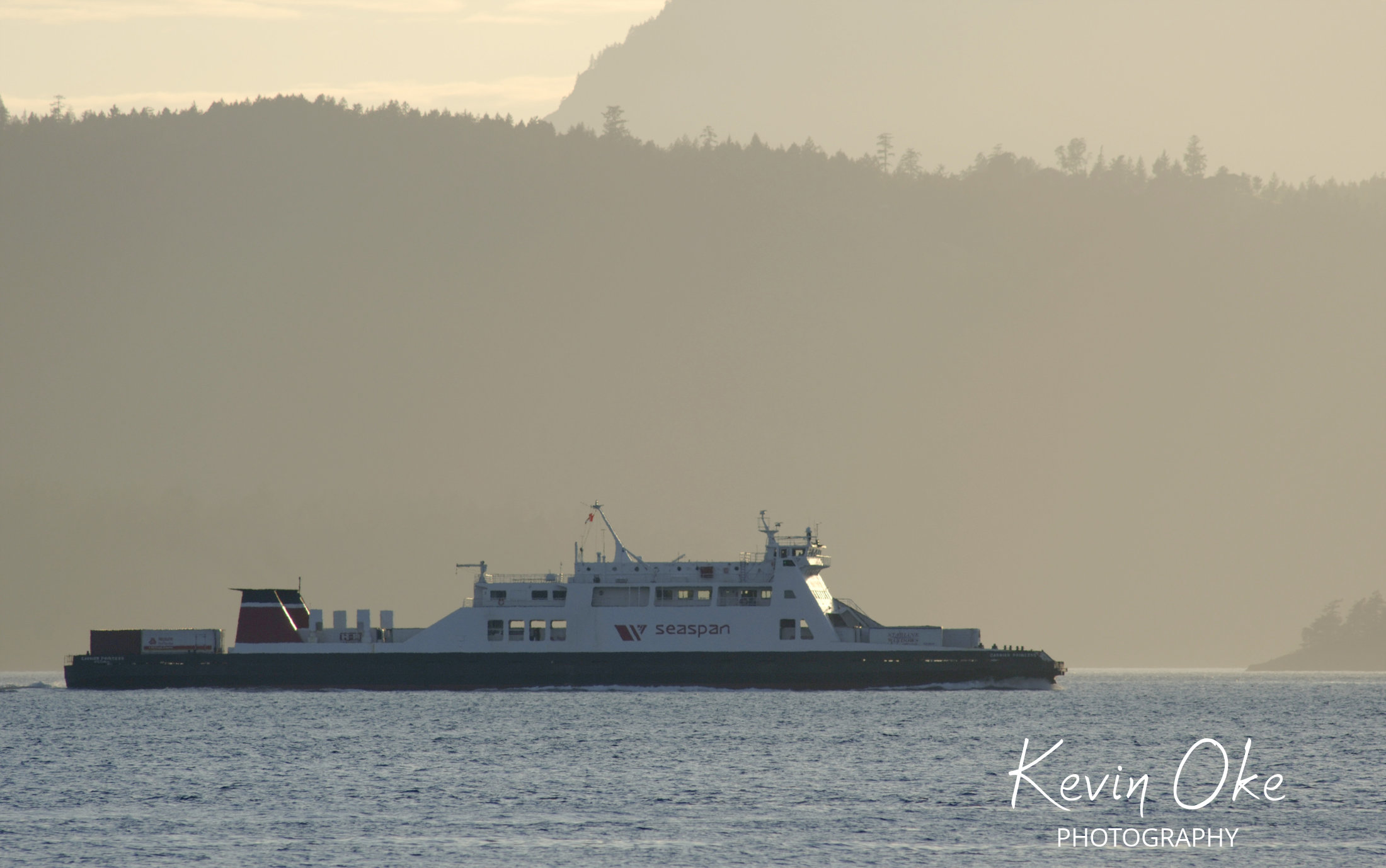 The freight ferry operated by Seaspan heads towards the lower mainland in front of Salt Spring Island and Prevost Island. The photograph is shot from Roe Islet at Roesland on North Pender Island, Gulf Islands, BC